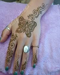 female hand and wrist decorated with a butterfly of hand and floral design on fingers and wrist in henna