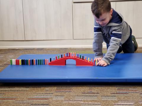 boy lining up dominos
