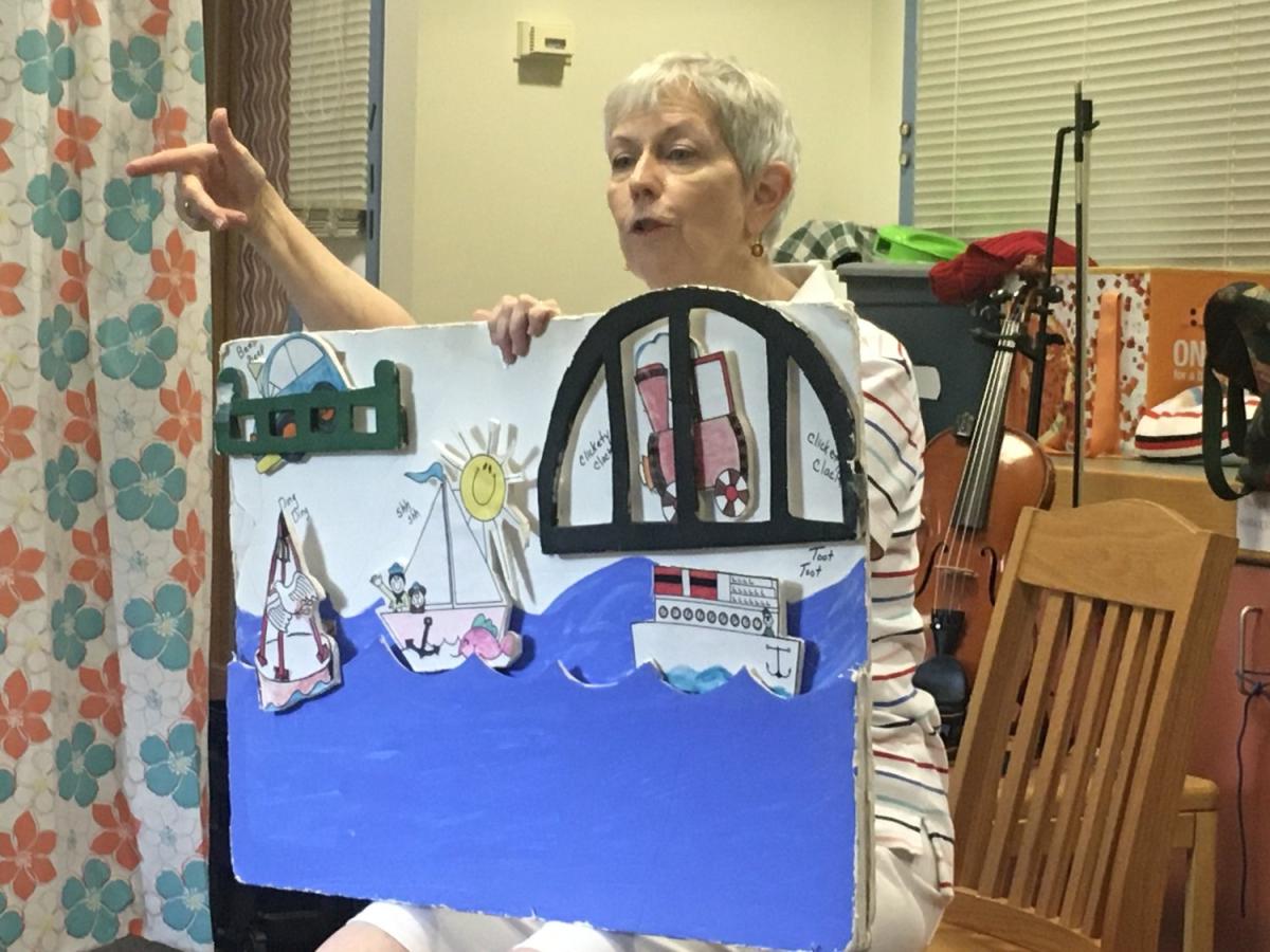 Female performer holding a sail and song activity board