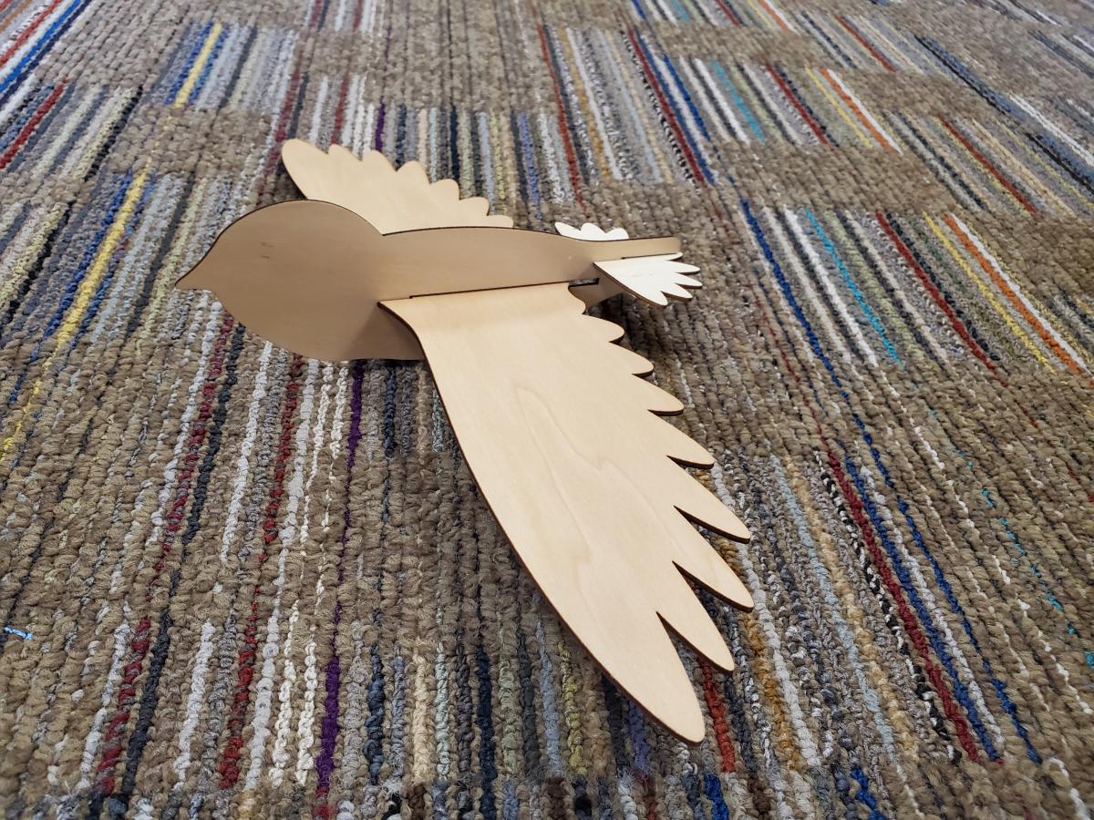 wooden bird glider on striped background